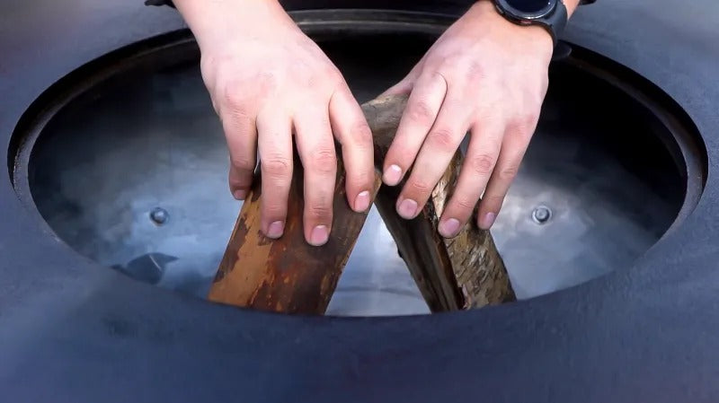 Loading the wood in a Mojave grill before starting a fire.