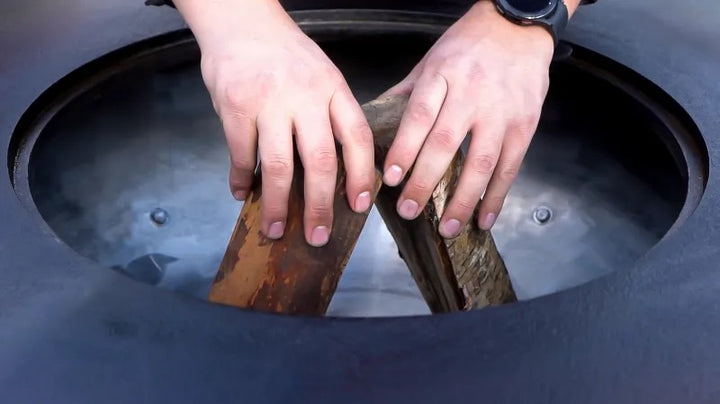 Loading the wood in a Mojave grill before starting a fire.