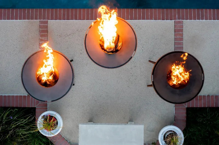 At top view of 3 flaming Mojave Grills - powder coated black, stainless steel and corten steel.