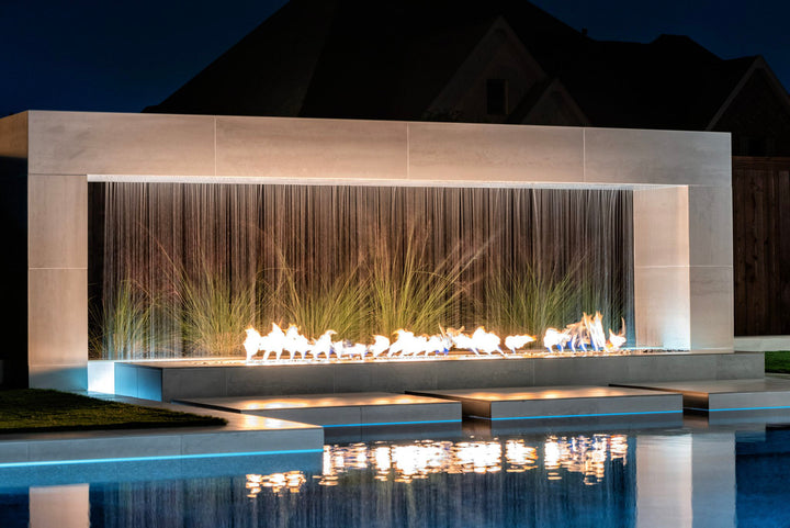 The Outdoor Plus Williams Fireplace with scupper at night poolside