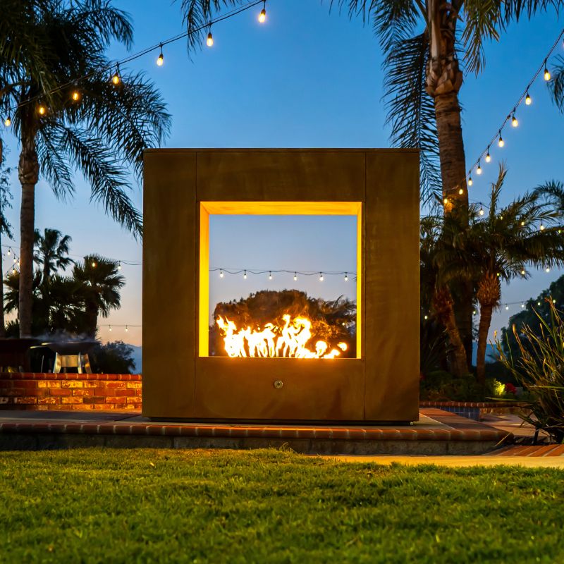 Square fireplace lit at night by the pool.