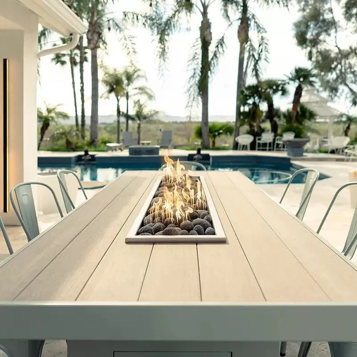 View of the beautiful wood top and polished lava rocks of a lit Alameda fire table.