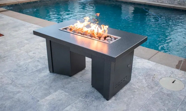 Alameda powder coated fire pit table lit  up poolside.