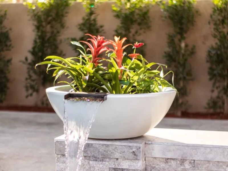 Sedona Planter Water Bowl GFRC Limestone with plants pouring water into a pool.
