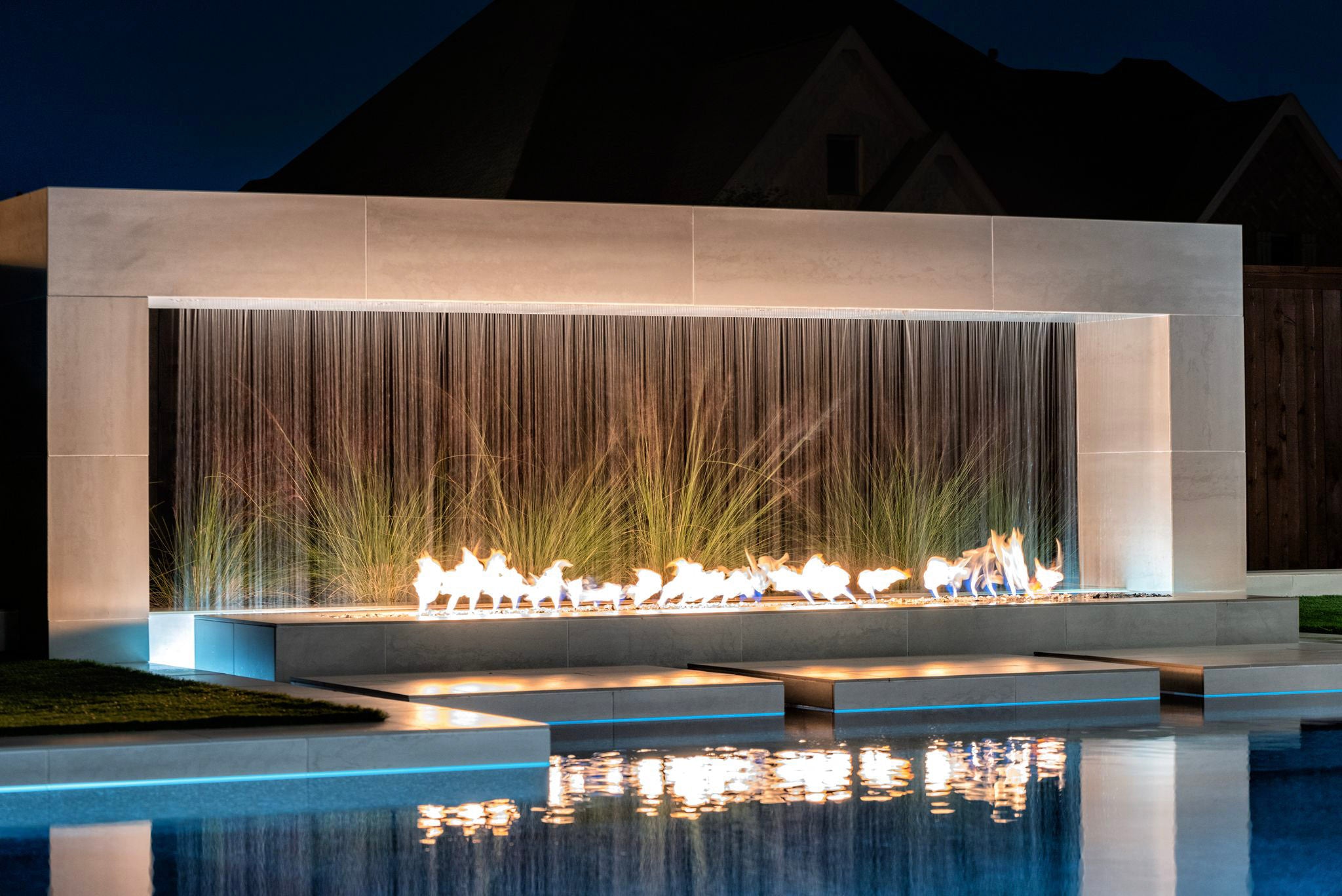 The Outdoor Plus Williams Fireplace with scupper at night poolside