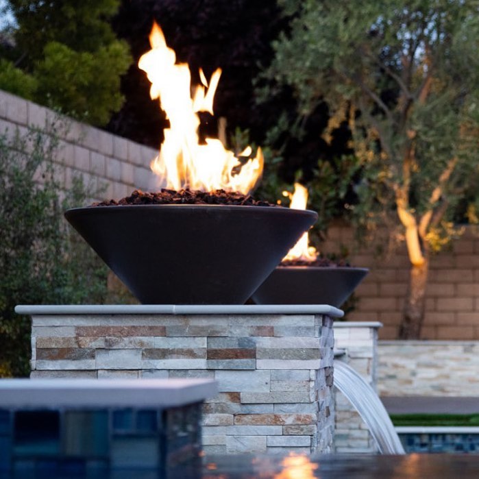 Cazo fire bowls with high bullet burner flames on a poolside fountain.